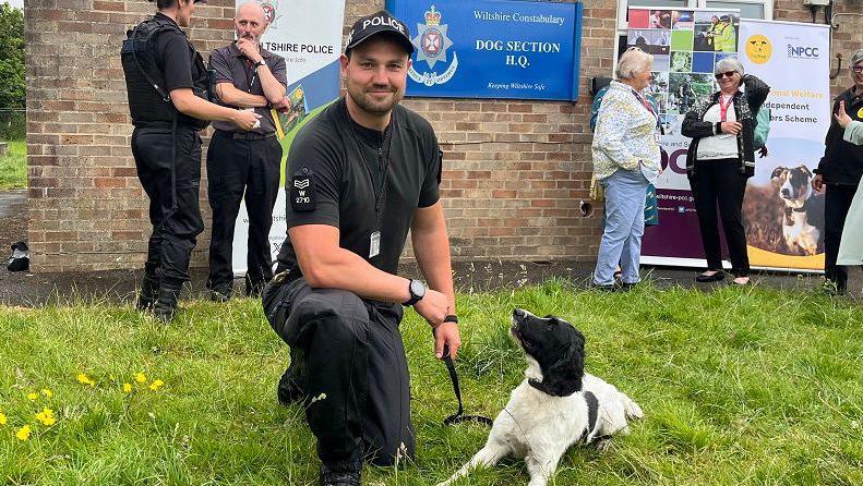 Police dog handler looking into the camera with spaniel-type dog on a lead