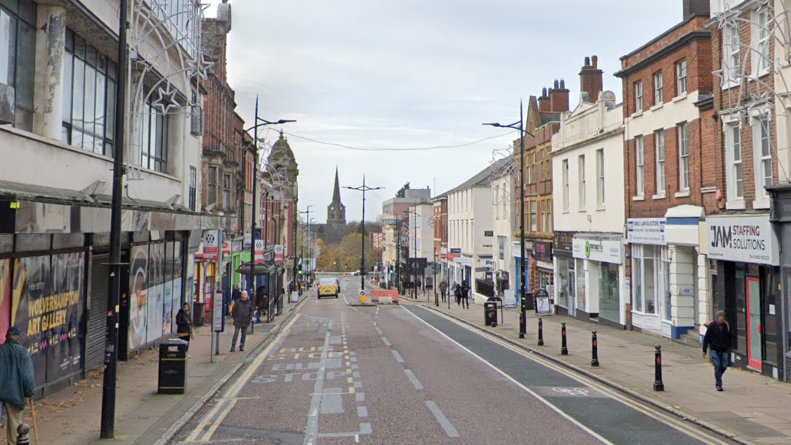 Darlington Street is a long street with buildings and shops on either side. In the distance is a church