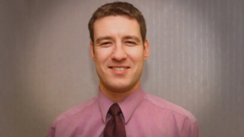 Family picture of a smiling Alistair Wilson in a pink shirt and tie