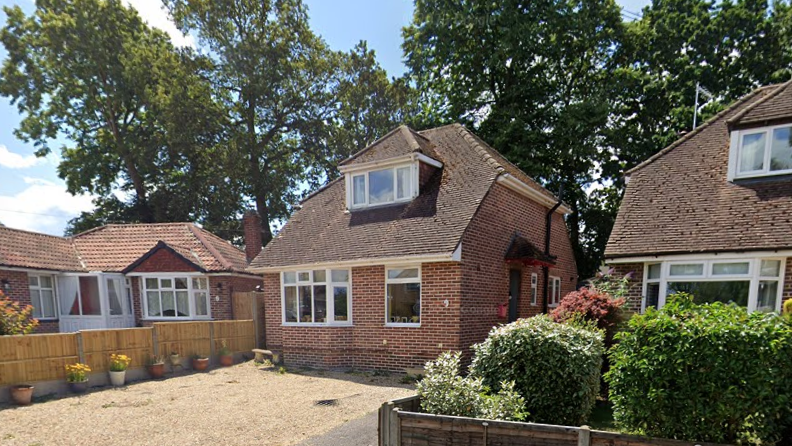 View from the street of 20 Southmead Road, Fareham, showing a bungalow with an upper level dormer window behind a gravelled front area. A row of tall trees are at the rear of the property.