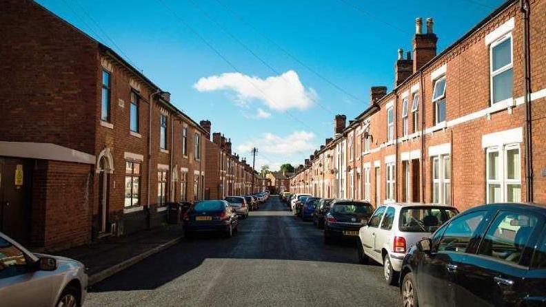 A general view of a row of terrace houses with cars parked outside