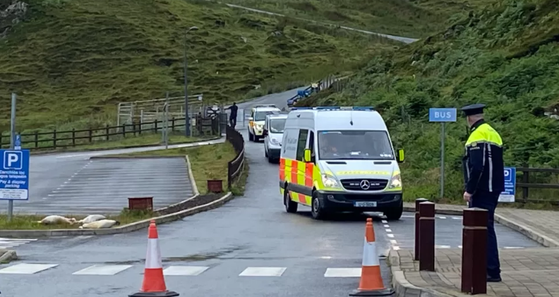 A garda stands in the foreground as a garda van pulls into a layby behind him 