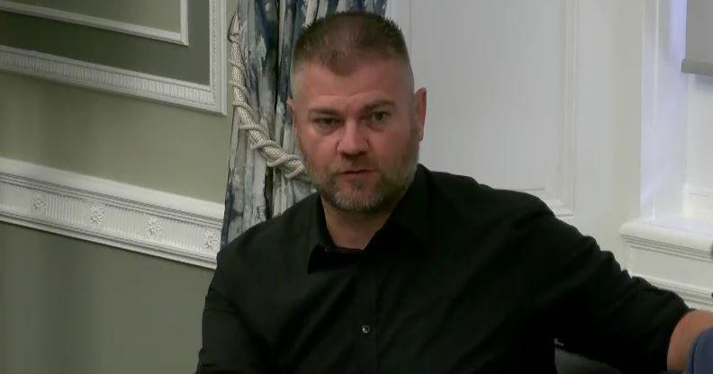 Colin McGrath has short cropped dark hair and a greying beard. He is wearing a dark shirt rolled up as the sleeves.