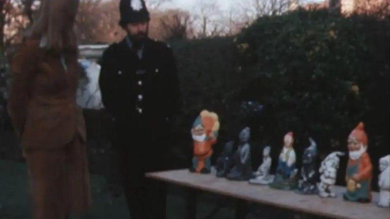 A police officer stood beside a table with eight different garden gnomes on top