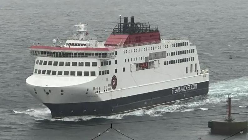 The Manxman ferry, which is in the Isle of Man Steam Packet Company's colours of red, white and black, sailing in Douglas Harbour on an overcast evening.