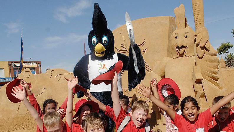 karak the black bird mascot holding a silver baton with kids