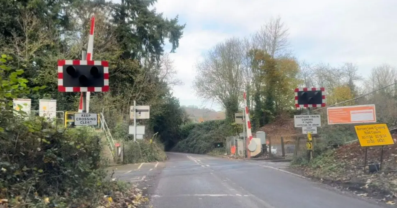 A picture of a level crossing with signs near it advertising of a closure