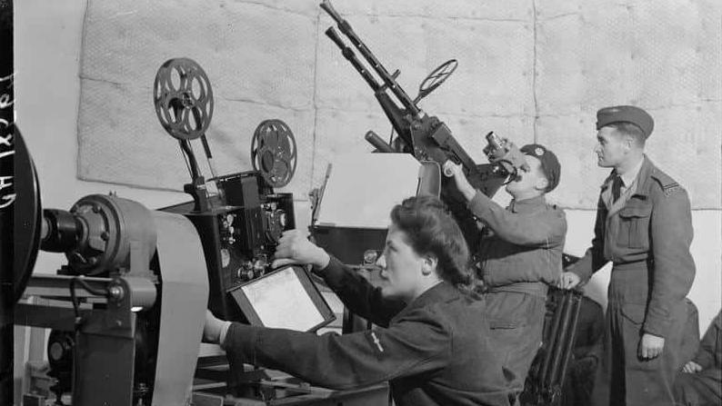 A member of the Royal Air Force Regiment under instruction in a dome anti-aircraft teacher at RAF Leuchars where a WAAF projects the film of the targets