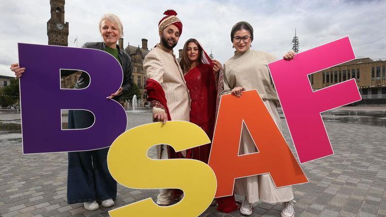 Four people holding brightly-coloured letters spelling out BSAF. 