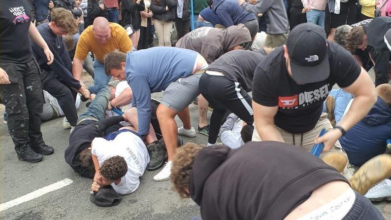 Fight involving a group of men, with some rolling around on the floor