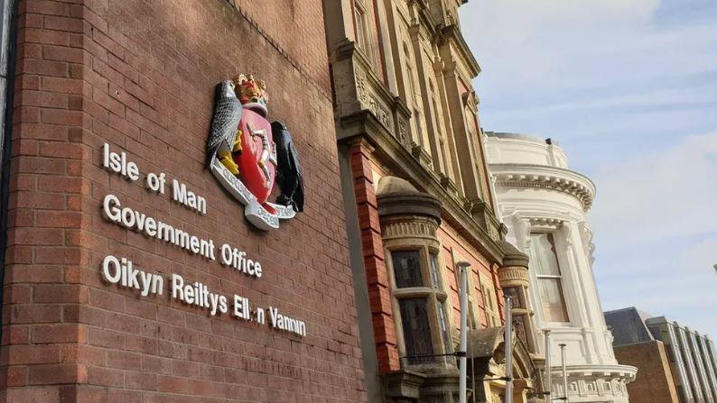 The outside of a red brick building with a government crest and lettering on the wall