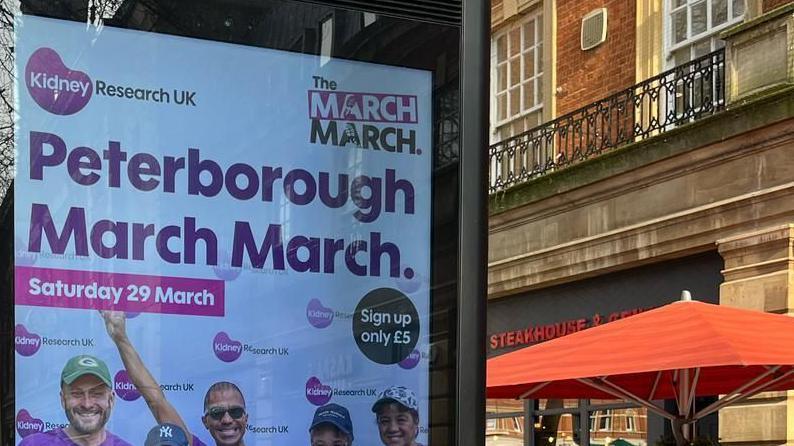 The top of a poster advertising the Kidney Research UK Peterborough March March. The words Saturday 29 March are written on a pink banner. The faces of four people can also be seen on the banner. 