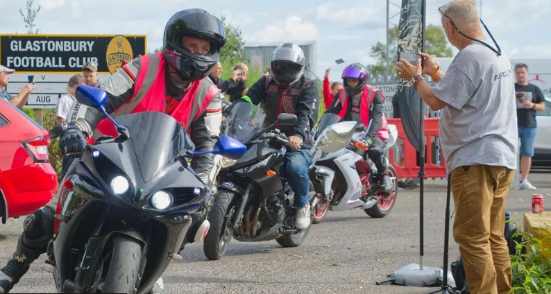 Lots of motorbikes gathered exiting a gravel car park