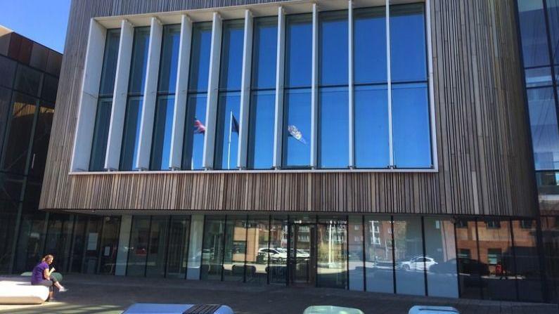 The outside of the civic centre in Redcar operated by Redcar and Cleveland Council. It has large windows and wooden cladding. Flags can be seen reflecting through the windows.