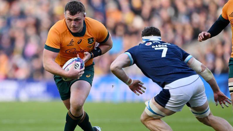 Angus Bell carries the ball against Scotland