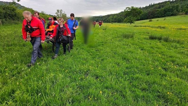 A rescue team carrying a stretcher across a field