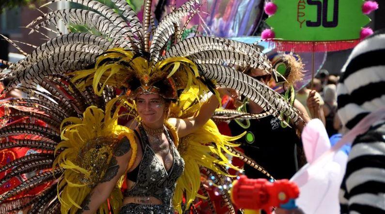 A woman in a bright, colourful headdress dancing on the streets of Bristol. 