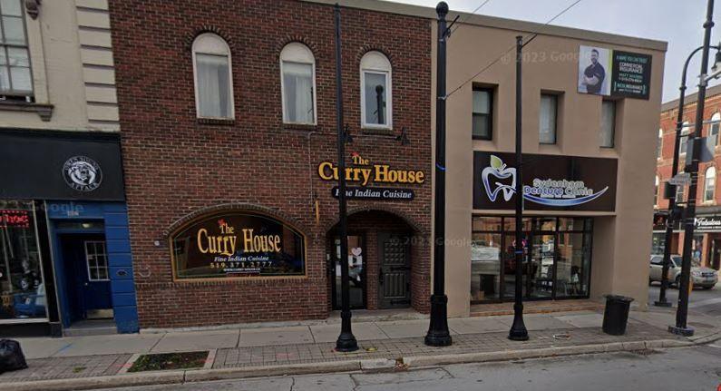 The exterior of a restaurant called the Curry House, a brick building set between two shops