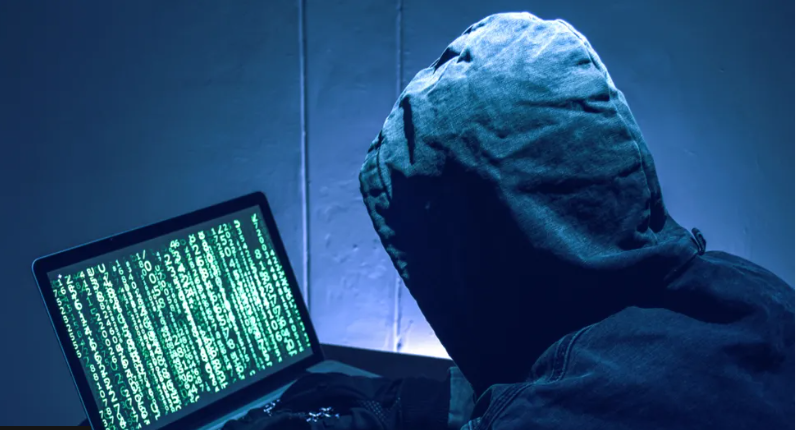 hooded man looking at a computer screen