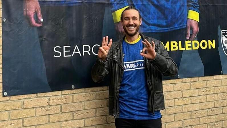 Graham Stacey holds up his hands to show 3-0, the scoreline by which AFC Wimbledon beat MK Dons in September