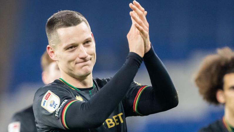 Zan Celar applauds the fans with big smile after scoring twice at Cardiff, wearing black QPR away kit
