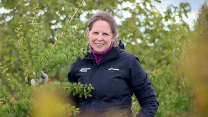 A woman stood in some bushes.