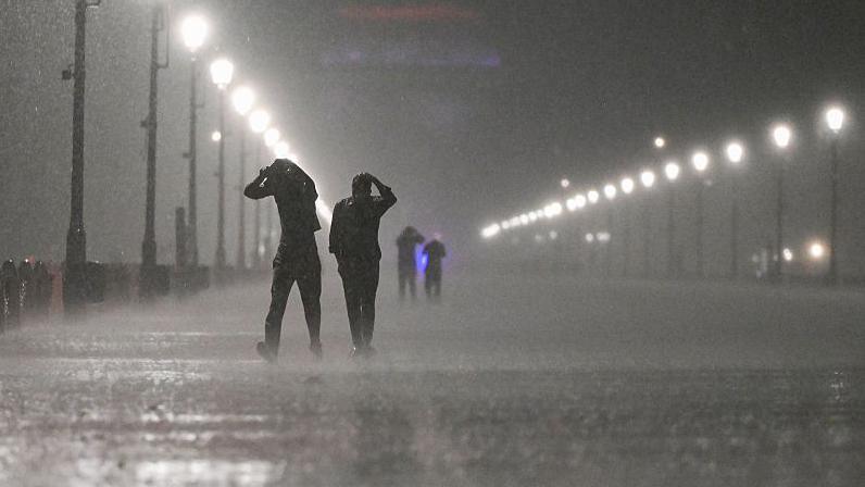 People seen covering their heads during heavy rainfall and a storm at Kartavyapath on May 21, 2025 in New Delhi, India.