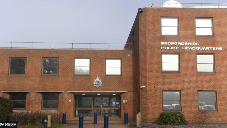 An external picture of Bedfordshire Police Headquarters - a red brick building with windows and glass doors.