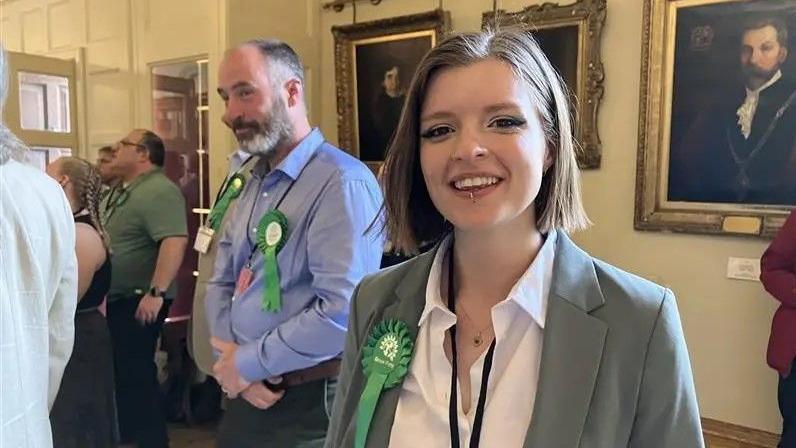 Councillor Tor Pingree poses for a photograph at Worcester's Guildhall after May's county council election results. Standing next to other Green candidates she is wearing a white shirt, green jacket and Green Party rosette