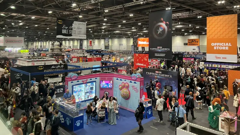 A view of a full expo hall, with hundreds of people milling about between colourful branded stalls.