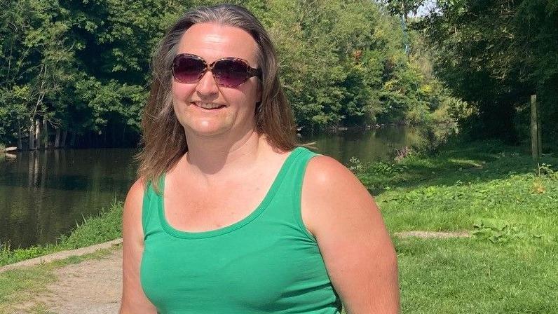 A woman in a green vest standing by the River Severn