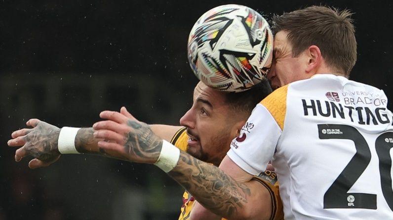 Courtney Baker-Richardson of Newport County looks to head at goal as Paul Huntington of Bradford City challenges 