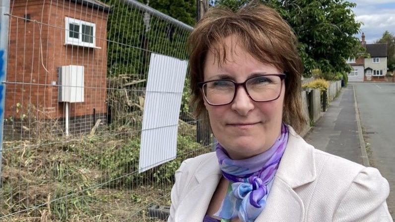 Sara Woodall standing in front of construction site fencing outside a property being renovated in Ludlow