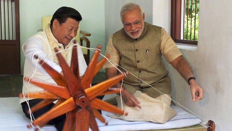 Modi and Xi seen sitting on flat white cushion as they work and Indian spinning wheel at the Sabarmati Ashram in Gujarat in 2014