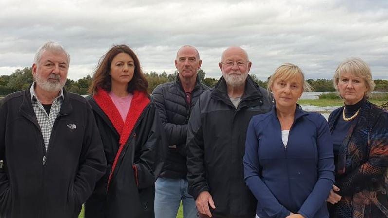 Six people stood looking into camera in a rural location