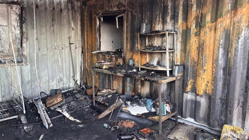 Fire damaged room. The room is black and charred. A worktop is badly damaged. Melted items are scattered on the floor.