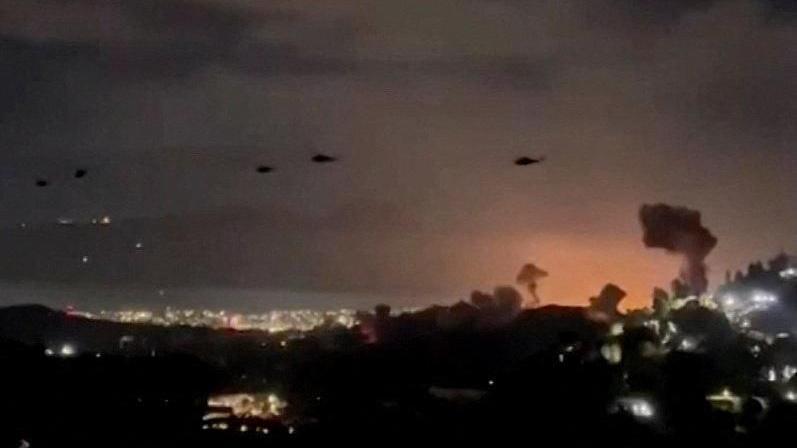 A grainy still from a video that shows at least five helicopters flying over the city as plumes of smoke can also be seen