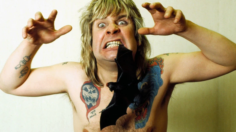 Ozzy Osbourne topless with toy bat in his mouth