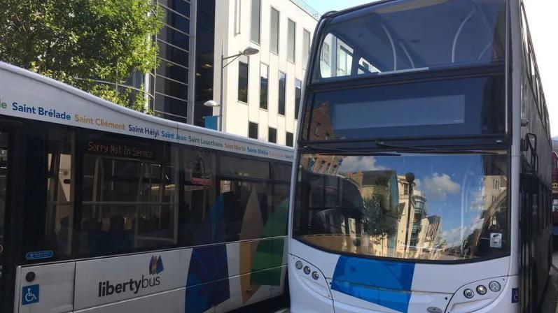 Two buses, one of which is a double decker, side by side from the front 