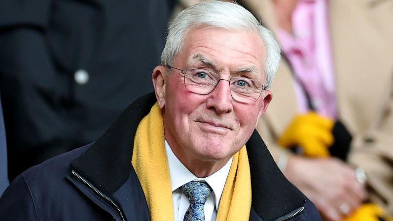 John Richards wearing glasses and a yellow scarf 