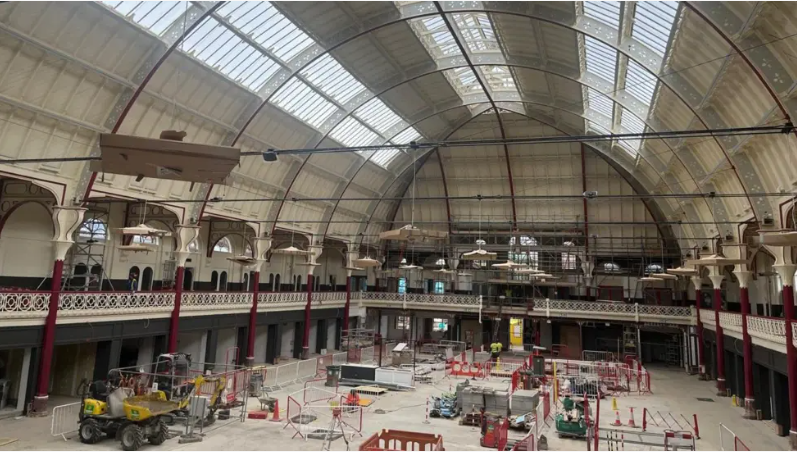 Large hall with rounded roof with windows on it, construction equipment inside the hall