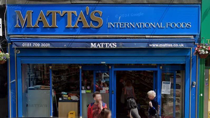 A blue shop front with the word Matta's in gold lettering and International Foods in white lettering.
