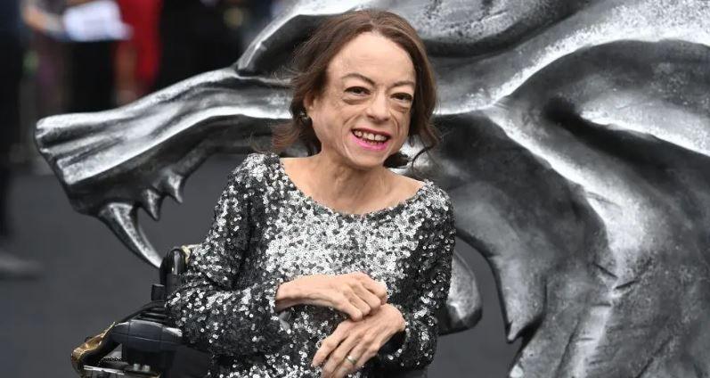 Liz Carr wears a sparkly dress and smiles in a portrait photograph