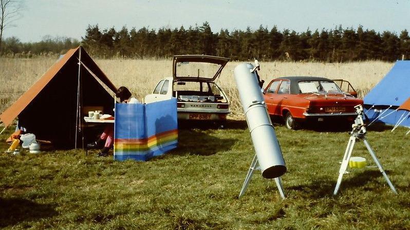 A picture from 1988 shows tents set up, cars parked and telescopes on grass. 