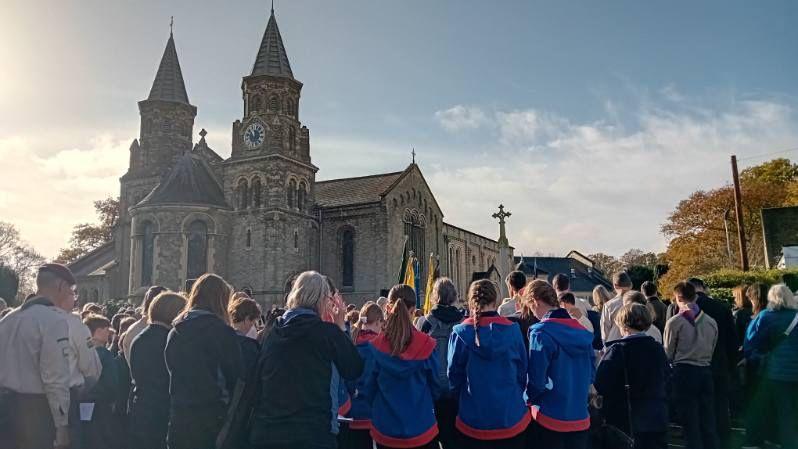People with their backs to camera outside a church in Claygate taking part in a memorial service