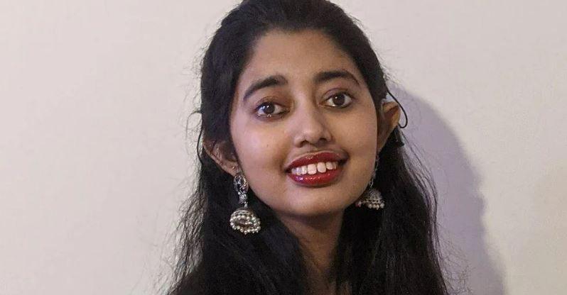 Sudiksha Thirumalesh, who has long dark hair, dark eyes and is wearing dangly earrings smiles at the camera