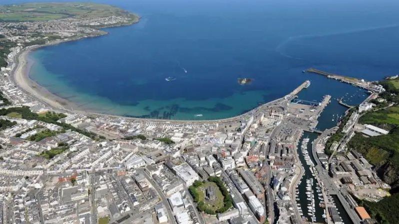 An aerial view of Douglas, which has an arching coastline and is densely populated with buildings.