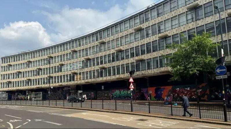 A large curved grey building with dozens of windows.