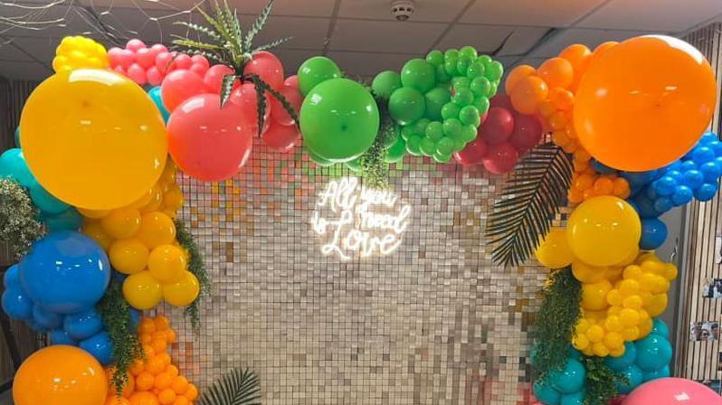 A balloon arch with "All you need is love" written in lights at Tondu RFC