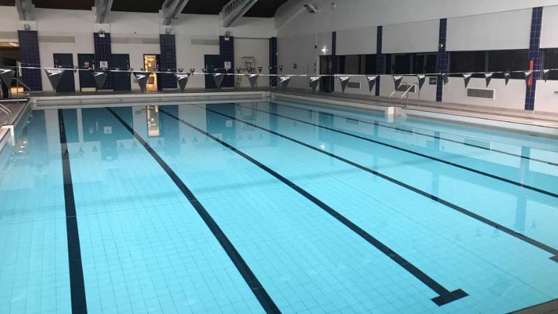 An empty blue pool which has black markings for lanes